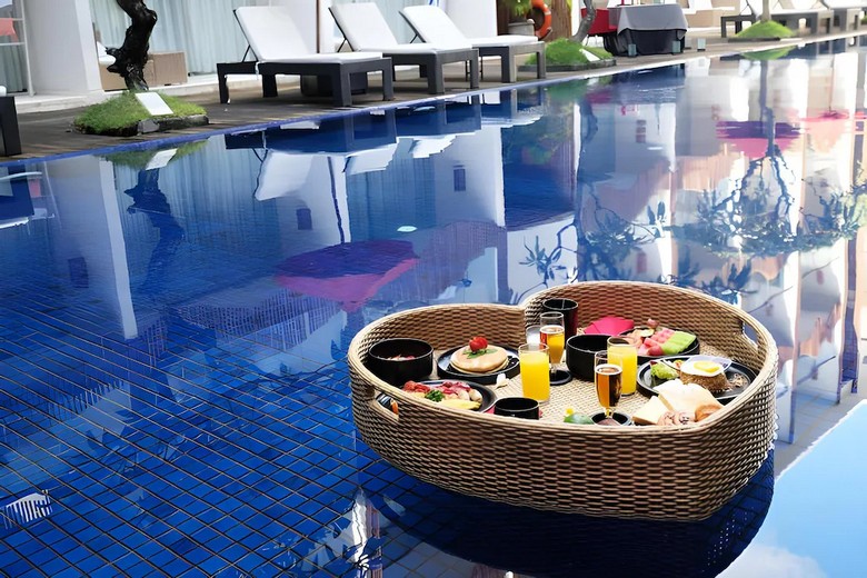 Bàn ăn sáng buffet tại khách sạn Kuta view hồ bơi, nắng sớm chiếu vào không gian mở