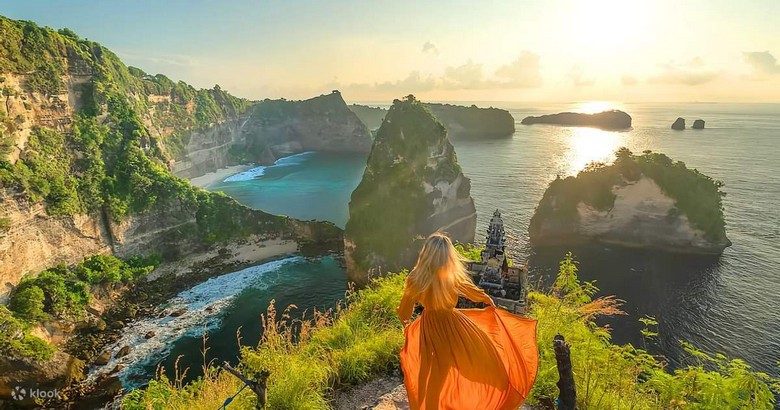 Hoàng hôn tại Crystal Bay Nusa Penida — bầu trời cam đỏ, bóng hòn đảo đá nhỏ phản chiếu trên mặt nước