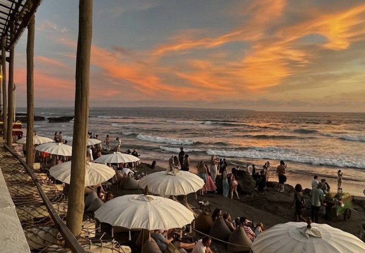 Bãi biển Canggu buổi chiều với người lướt sóng và quán cà phê ven biển