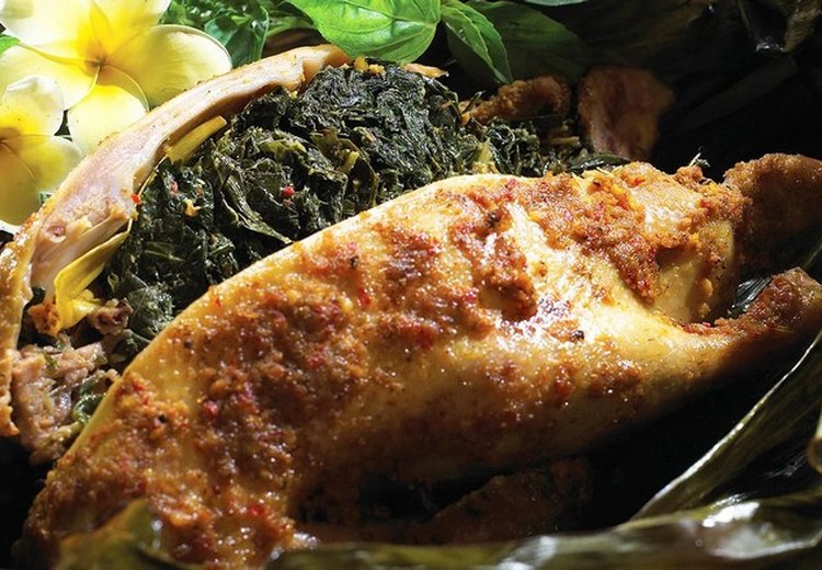 Bebek Betutu bọc lá chuối đang được mở ra, khói thơm bay lên, bày trên lá chuối xanh