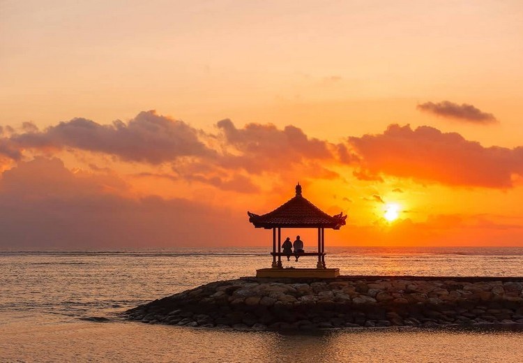 Bình minh trên bãi biển Sanur, ánh sáng vàng nhạt chiếu, biển phẳng lặng như gương