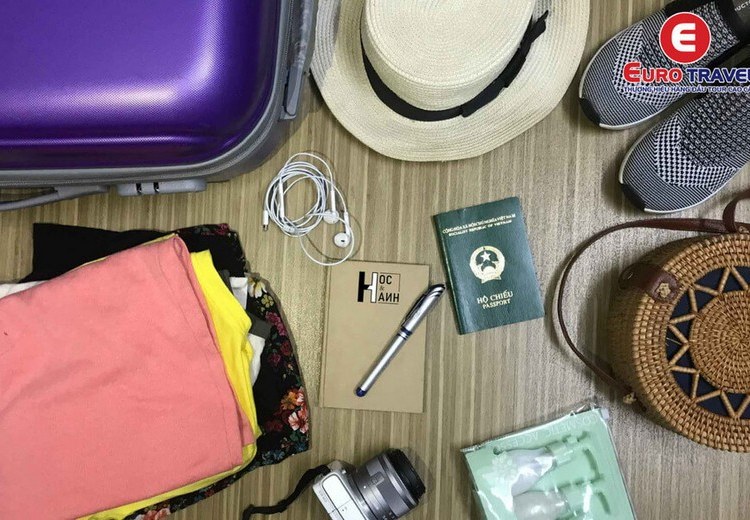 Checklist hành lý du lịch Bali xếp gọn trên bàn: kem chống nắng, sarong, dép sandal, hộ chiếu