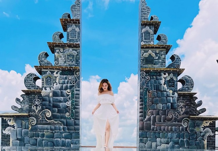 Cô gái mặc váy boho màu trắng đứng trước cổng đền Lempuyang buổi sáng sớm
