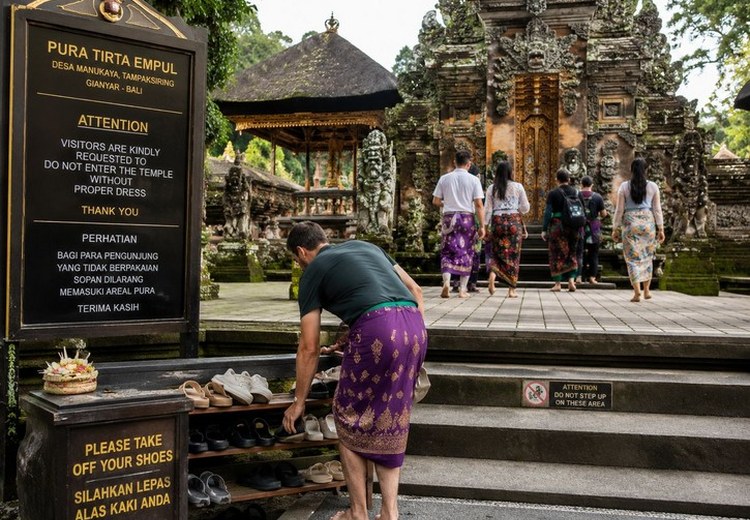 Du khách cởi giày trước khi vào điện thờ chính trong một ngôi đền tại Ubud, Bali