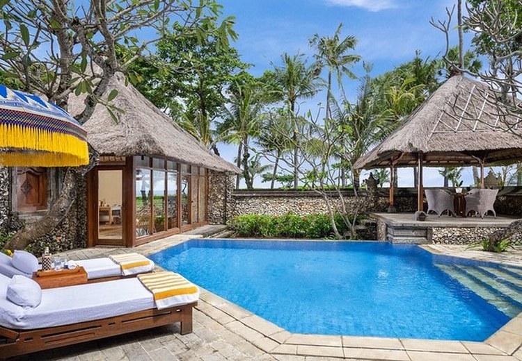 Hồ bơi villa Bali view vườn nhiệt đới với ghế tắm nắng và dù che