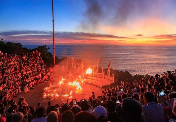 hoàng hôn đỏ rực sau sân khấu múa Kecak tại Uluwatu — cảnh bầu trời và biển phía sau đoàn múa, góc chụp từ khán đài