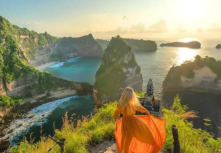 Hoàng hôn tại Crystal Bay Nusa Penida — bầu trời cam đỏ, bóng hòn đảo đá nhỏ phản chiếu trên mặt nước