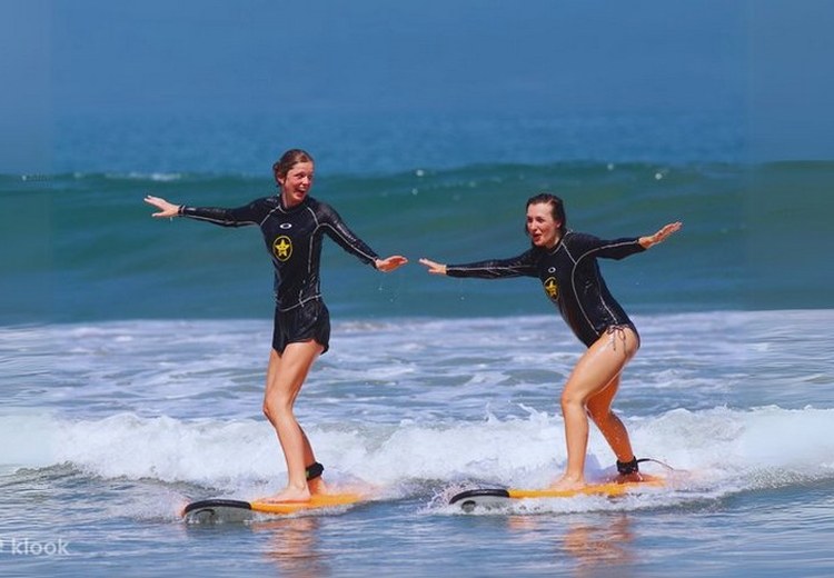 Học viên đang tập đứng trên ván surf cùng huấn luyện viên người Bali tại bãi Kuta