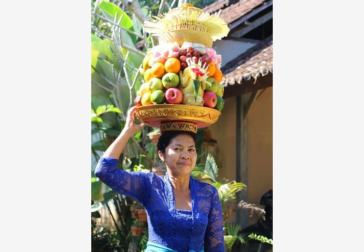 Lễ vật hoa, trái cây và nhang được người phụ nữ Bali dâng lên bàn thờ nhỏ trước cửa nhà vào buổi sáng