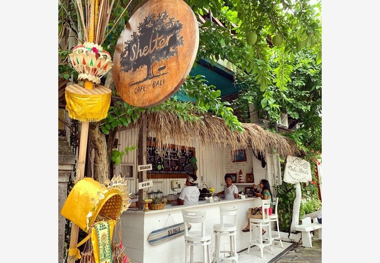 Một góc quán cà phê healthy tại Ubud với bàn gỗ, cây xanh và bát açaí bowl đầy màu sắc