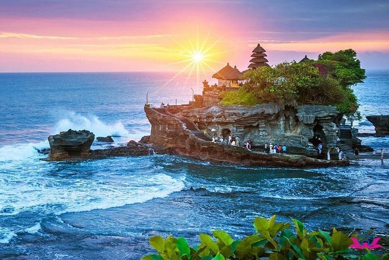 Đền Tanah Lot nhìn từ bãi đá phía tây, hoàng hôn đỏ rực phía sau ngôi đền giữa biển